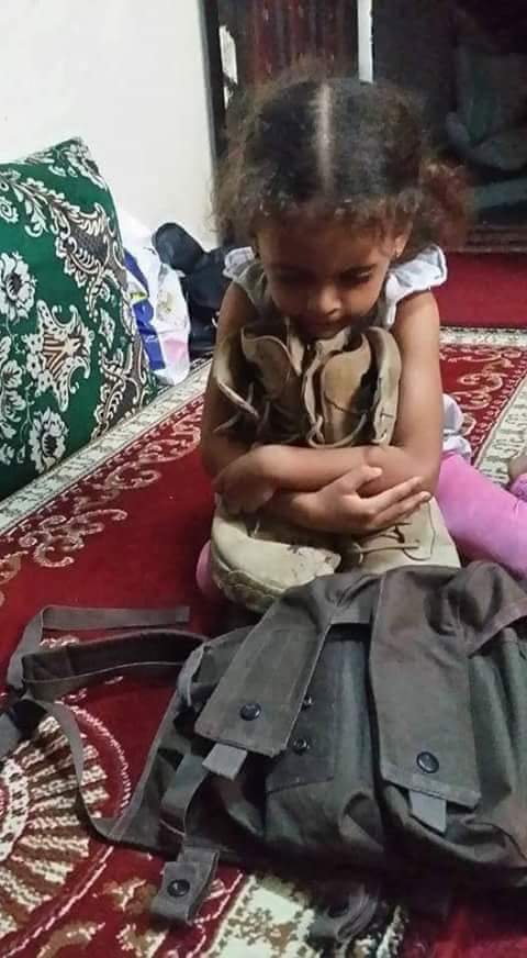 ( صورة مؤثرة ) ابنة احد شهداء مجزرة مأرب تحتضن ماتبقى من ذكريات ابيها